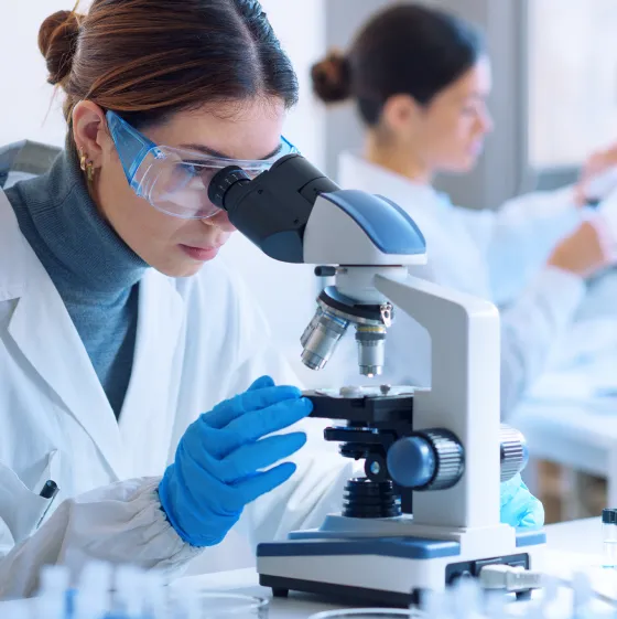 Young scientists conducting research investigations in a medical laboratory, a researcher in the foreground is using a microscope